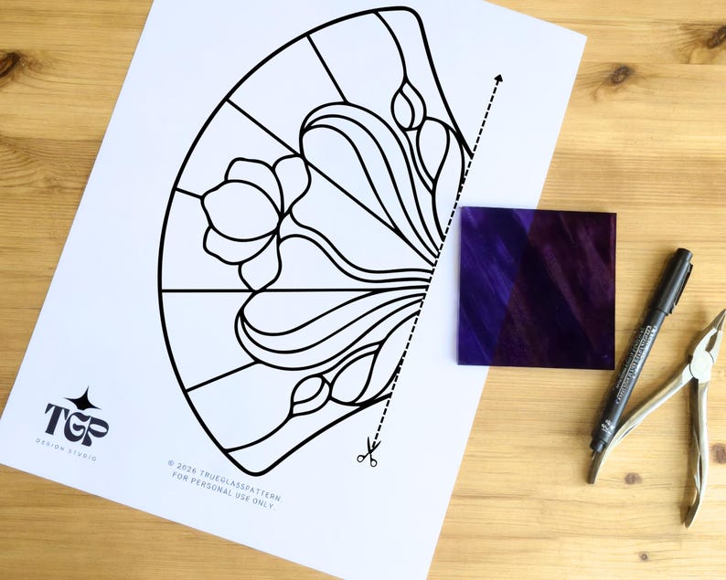 Printed stained glass pattern beside glass pieces and tools